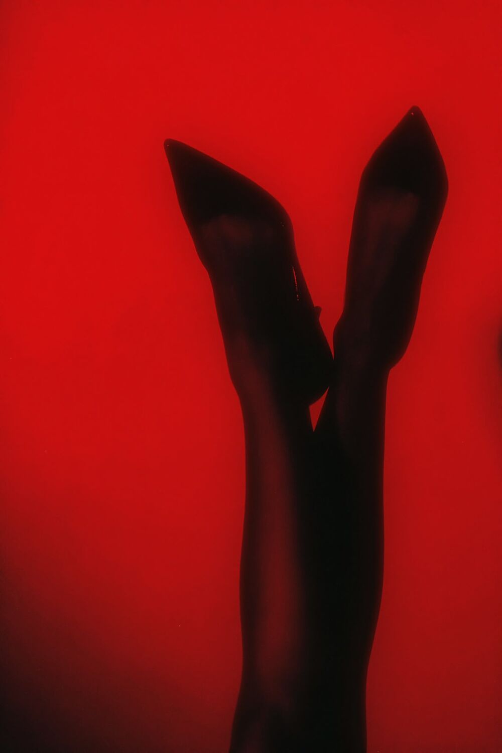 Crossed stiletto heels against deep red